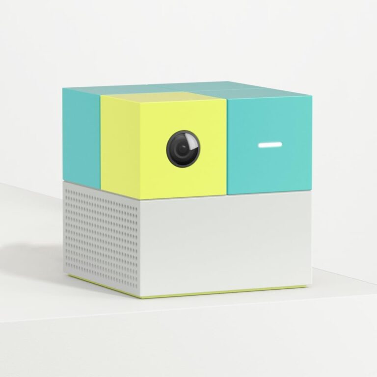 Colorful, cube-shaped camera with a lens, button, and perforated bottom section