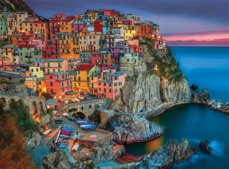 Colorful buildings on a cliffside overlooking the ocean at dusk